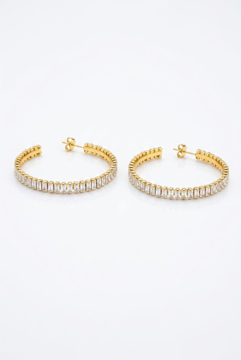 Gold hoop earrings with clear gemstones on a white background